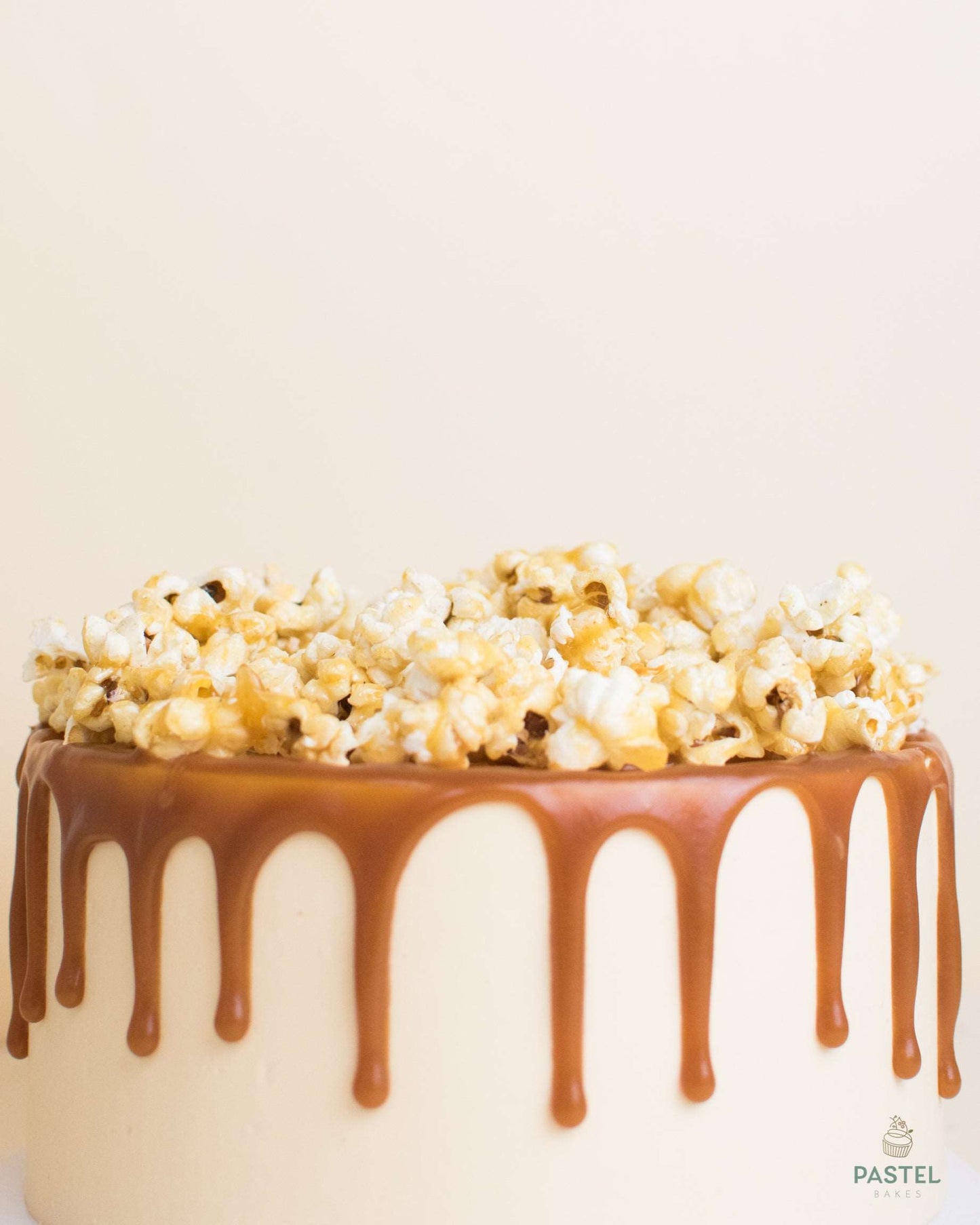 Caramel popcorn cake with salt caramel drizzle and a mountain of caramel popcorn on top of it