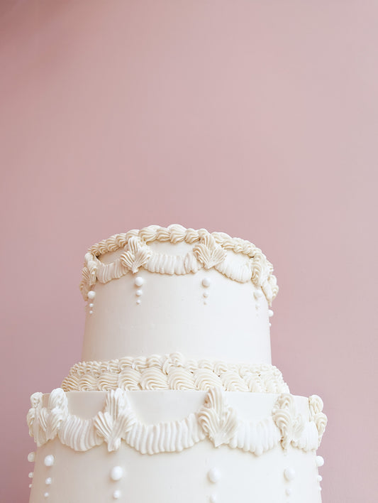 White tiered vintage cake with massive cream decor