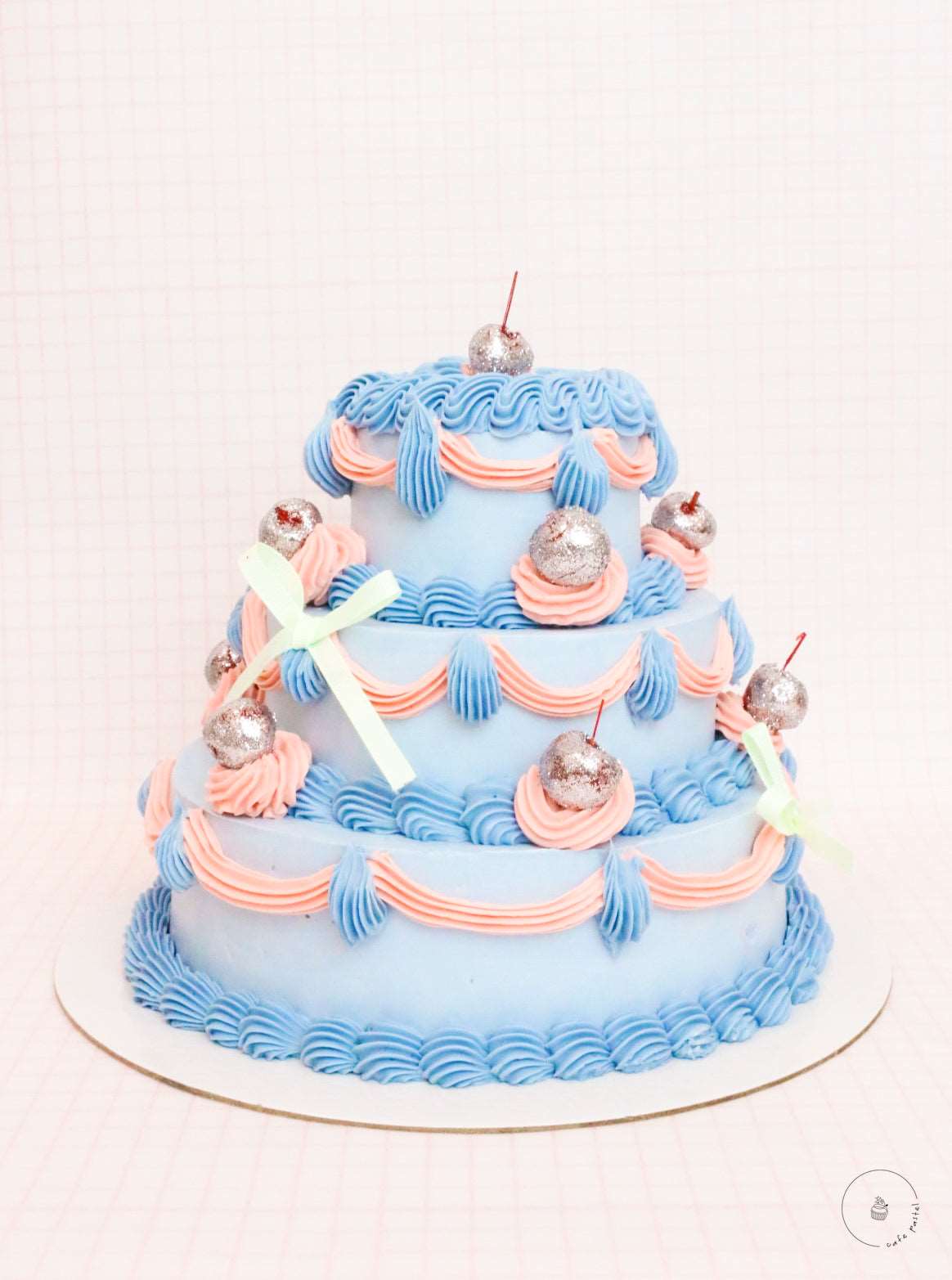 Blue 3 layers tiered cake with glittery cherries and finished with pretty ribbons