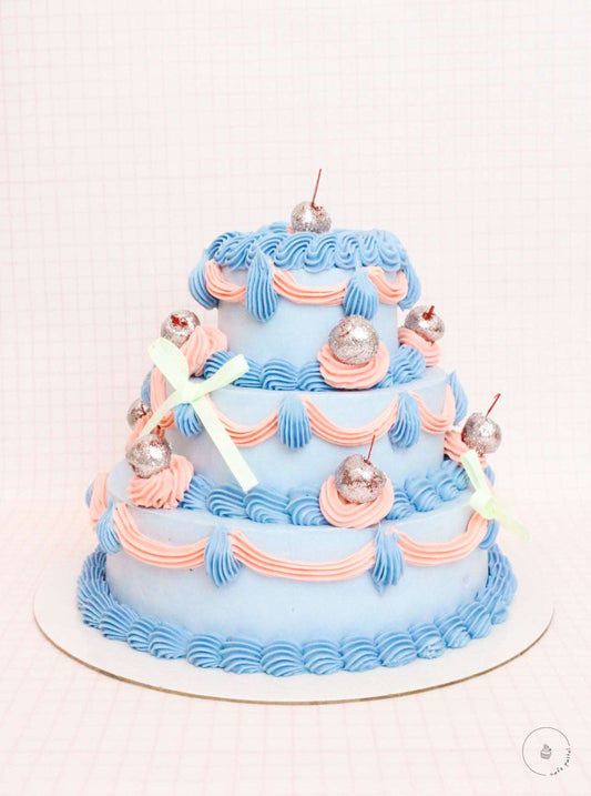 Blue 3 layers tiered cake with glittery cherries and finished with pretty ribbons