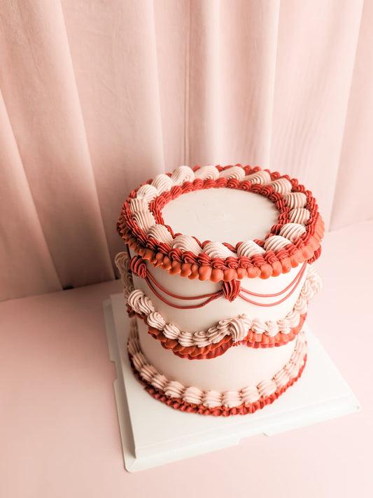 Peachy Red Lambeth Cake with red and pink cream ruffles on top, middle, and bottom of the cake.